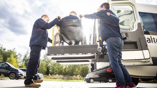 Zwei Mitarbeitende des Malteser Fahrdienstes helfen einer Person im Rollstuhl.