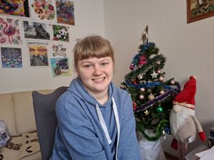 Eine junge Frau schaut lächeln in die Kamera.