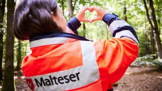 Malteser Mitarbeiterin macht mit den Fingern ein Herz