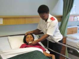 A nurse tends to a patient lying in a hospice bed.