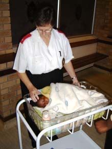 A nurse examines an infant lying in a cot.