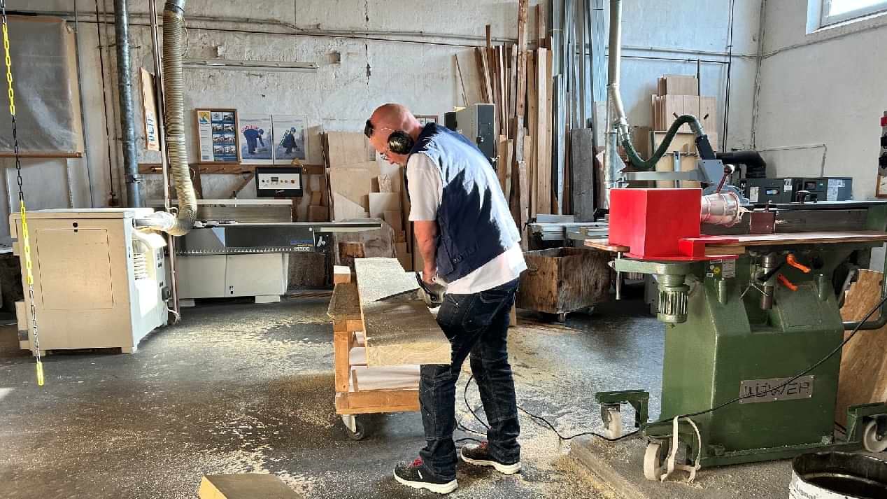 Ein Mann, der in einer Tischlerei an einem Holzbrett arbeitet.