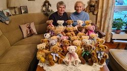 Zwei Frauen sitzen auf einem Sofa umgeben von Stoffbären.