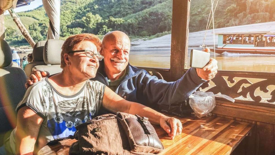 Es wird ein älteres Seniorenpaar gezeigt, welche eine Bootstour genießen.