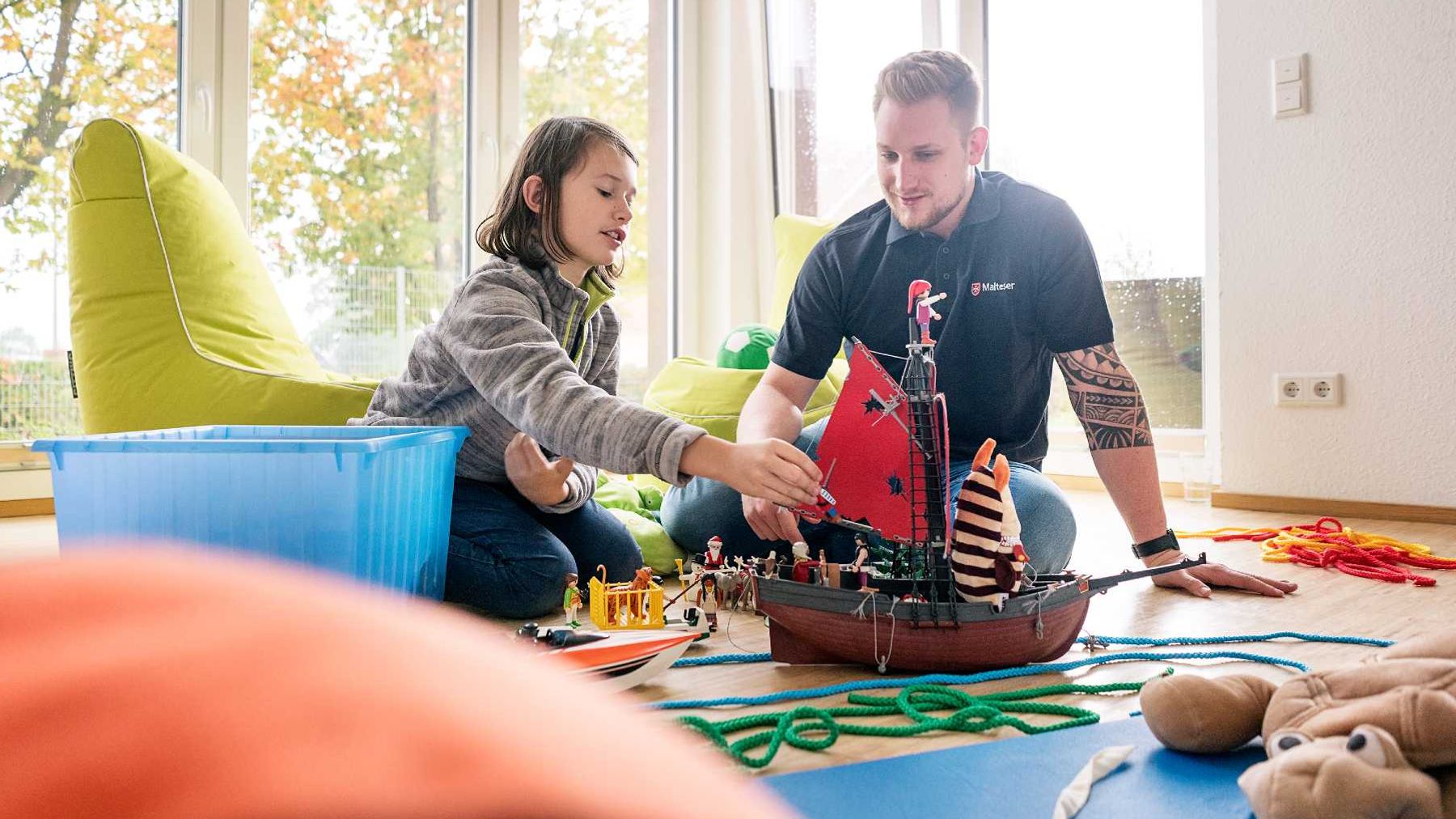 Mitarbeiter der Kinder- und Jugendhilfe der Malteser spielt mit einem Kind 