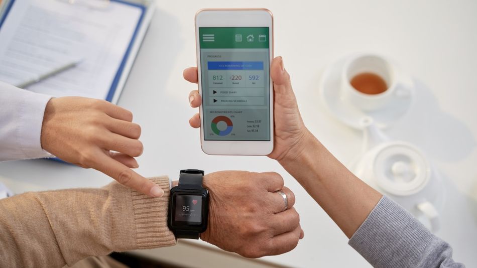 Ein älterer Mensch trägt eine Smartwatch am Handgelenk, aus der Gesundheitsdaten ausgelesen werden