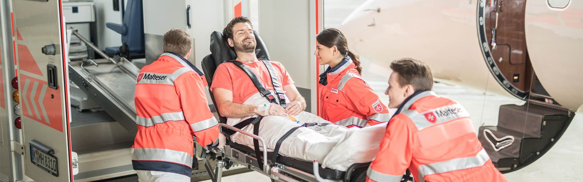 Ein Mann wird von einem Flugzeug in einen Rettungswagen verladen