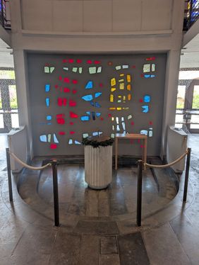 Taufbecken der Kolumbariumskirche Osnabrück vor einer Wand mit Farbakzenten durch farbiges Glas und Tageslicht