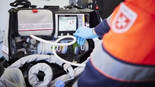 Sanitäter bedient ein Beatmungsgerät im Rettungsdienst mit Handschuhen und Notfallausrüstung.