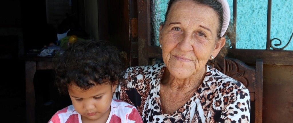 A picture of an senior woman from Venezuela with her grandchild in front of their appartement