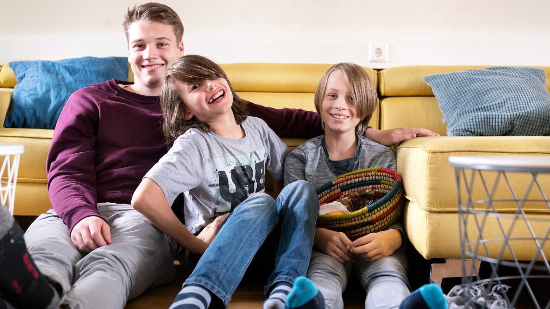 Junger Mann mit zwei Kindern vor einem Sofa