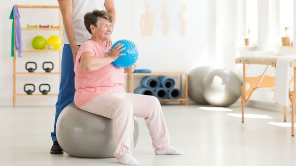 Eine ältere Frau auf einem Gymnastikball.