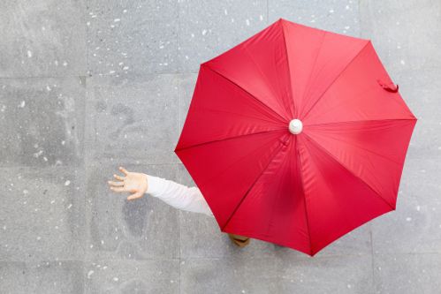 geöffneter roter Regenschirm, linke Hand schaut auf der Seite raus