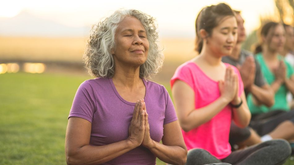 Eine ältere Frau mit geschlossenen Augen; dahinter weitere Personen in gleicher Pose. 
