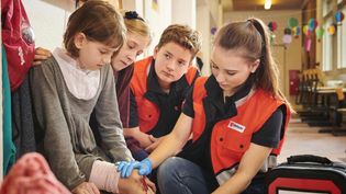 Schulsanis versorgen verletzte Mitschülerin im Schulflur