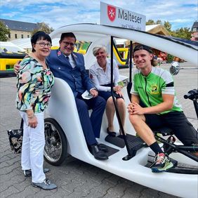 Mehrere Personen stehen an einer Fahrradrikscha.