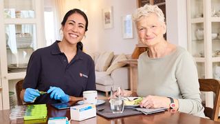 Mitarbeiterin des ambulanten Pflegedienstes gibt Patientin Medikamente.