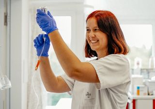Pflegekraft bereitet eine Infusion vor und trägt blaue Handschuhe.