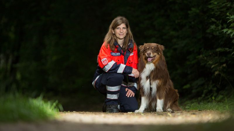 Eine knieende Frau mit einem Hund auf einem Waldweg