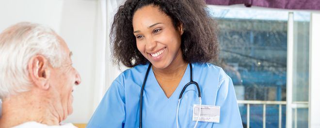 Eine Pflegekraft spricht mit einem älteren Menschen.