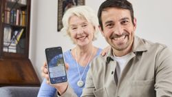 Mutter und Sohn sitzen glücklich auf einem Sofa, der Sohn hält sein Handy mit der HNR+-App in die Kamera