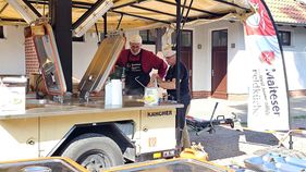 Zwei Männer der Malteser arbeiten an einer Feldküche.