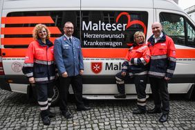 Malteser Mitarbeiter vor dem Herzenswunsch-Krankenwagen.
