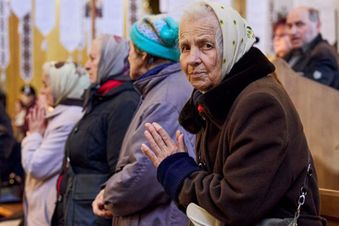Eine ältere Frau ist gestützt auf eine Gehhilfe und betet. Foto: Malteser Ukraine