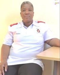 Sr. Phumzile Mbatha seated at a table in a white care uniform.
