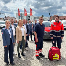 Eine Gruppe von Personen aus den Bereichen Rettungsdienst, Krankenhaus und Landkreis steht vor einem Akut-Einsatzfahrzeug der Malteser.