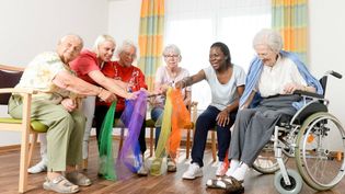 Ältere, sitzende Frauen halten bunte Tücher.