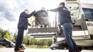 Zwei Mitarbeitende des Malteser Fahrdienstes helfen einer Person im Rollstuhl.