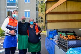 Drei Malteser vom Katastrophenschutz stehen Versorgungswagen und grillen.