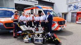 Das Foto zeigt v.l.n.r. die Rettungskräfte Luca Graziano, Josef Ibach, Lena Schwaiger, Nicole Konzelmann, Johannes Pfister, Svenja Tschuk, mit Dienststellenleiter Thomas Linhart und Arndt Ständer, Vorsitzender der Bezirksvereinigung der Volks- und Raiffeisenbanken im Zollernalbkreis. Die Gruppe steht vor der Rettungswache in Albstadt-Tailfingen. Im Hintergrund sind ein Krankentransportwagen (KTW) und ein Rettungswagen (RTW) zu sehen. Im Vordergrund steht eine Fahrtrage auf der viele Plüsch-Elefanten sitzen. Vor der Trage steht medizinisches Materiasl.