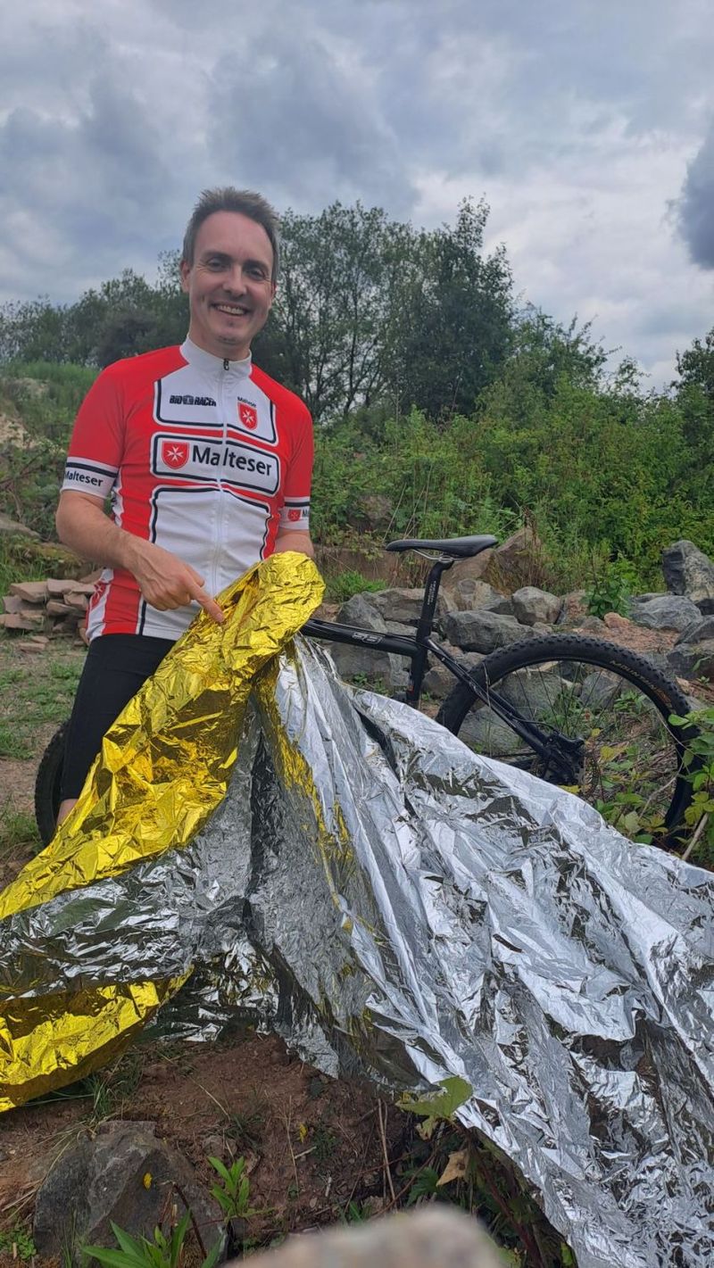 Ein lächelnder Mann mit Rettungsdecke in der Natur