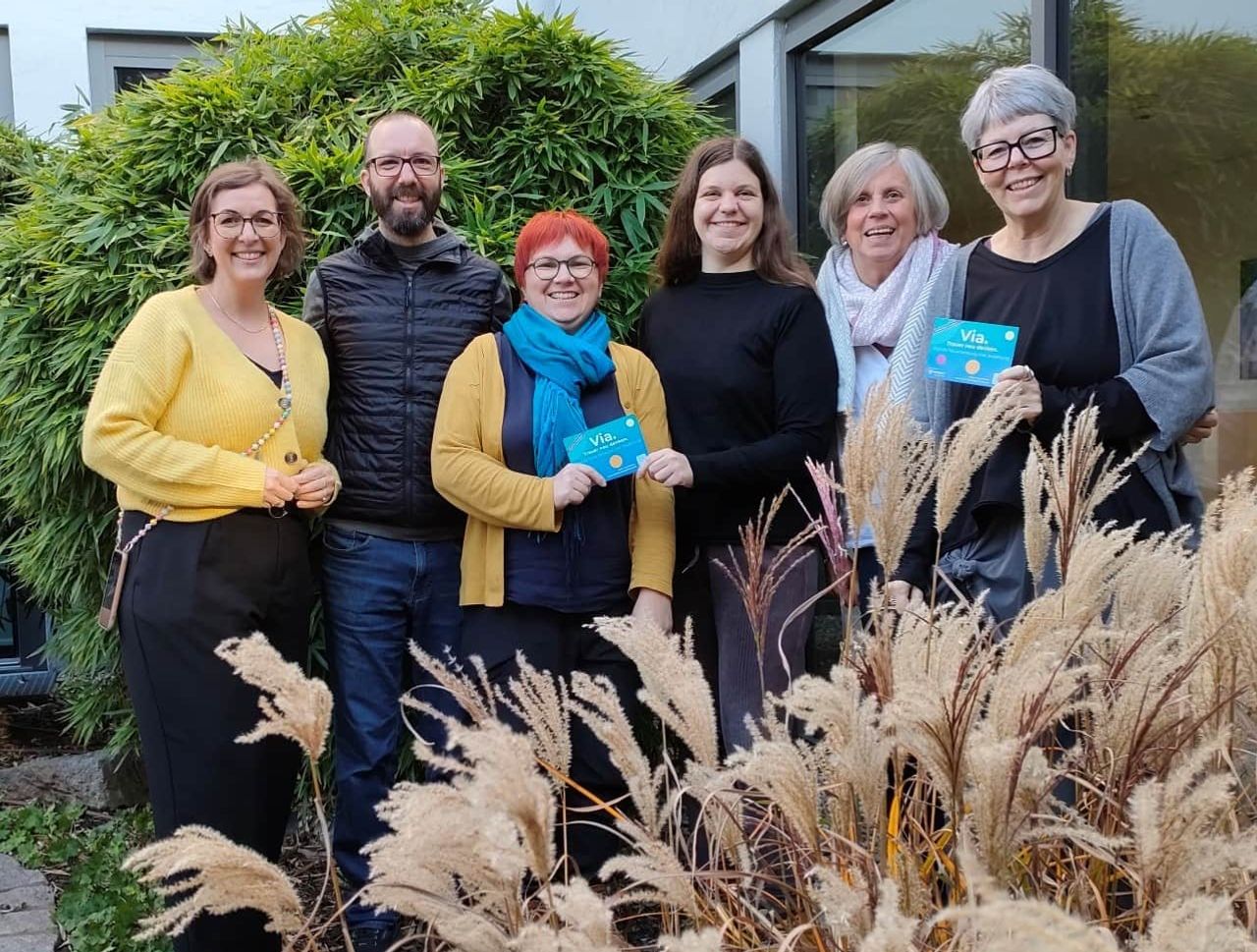 Mitarbeitende von Via stehen draußen und lächeln in die Kamera