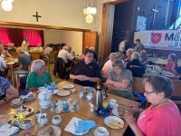 Panoramaaufnahme des Frühstücks, viele Menschen sitzen zusammen, reden und essen