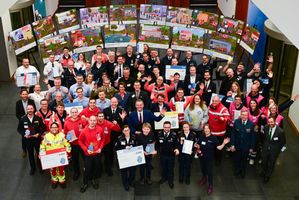 Viele Menschen mit freudigen Gesichtern winken in die Kamera.