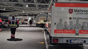 Zu sehen ist der Ankunftsbereich am Flughafen Terminal vor dem mehrere Einsatzfahrzeuge der Malteser stehen.es Terminal