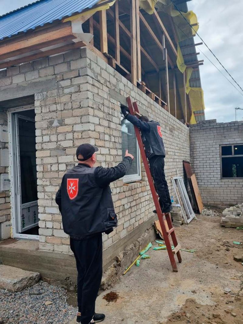 Zwei Männer setzen ein neues Fenster in ein Haus ein.