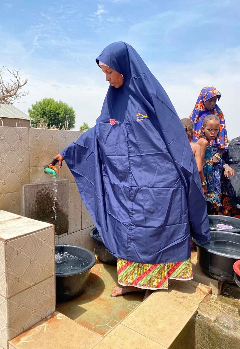 Eine Frau füllt eine Kunststoffwanne mit Wasser aus einem Hahn.