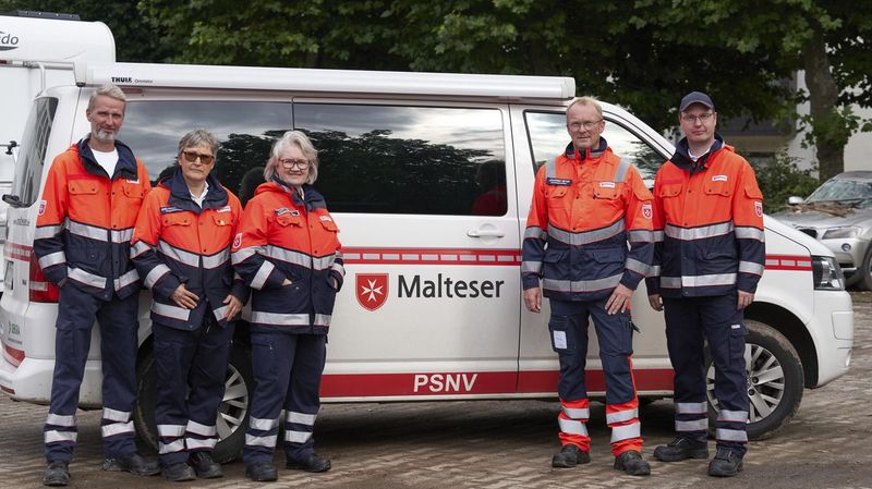 Angehörige der “Psychosozialen Notfallversorgung” der Malteser vor einem Einsatzfahrzeug.