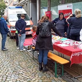 Mehrere Frauen stehen an einem Informationsstand der Malteser.