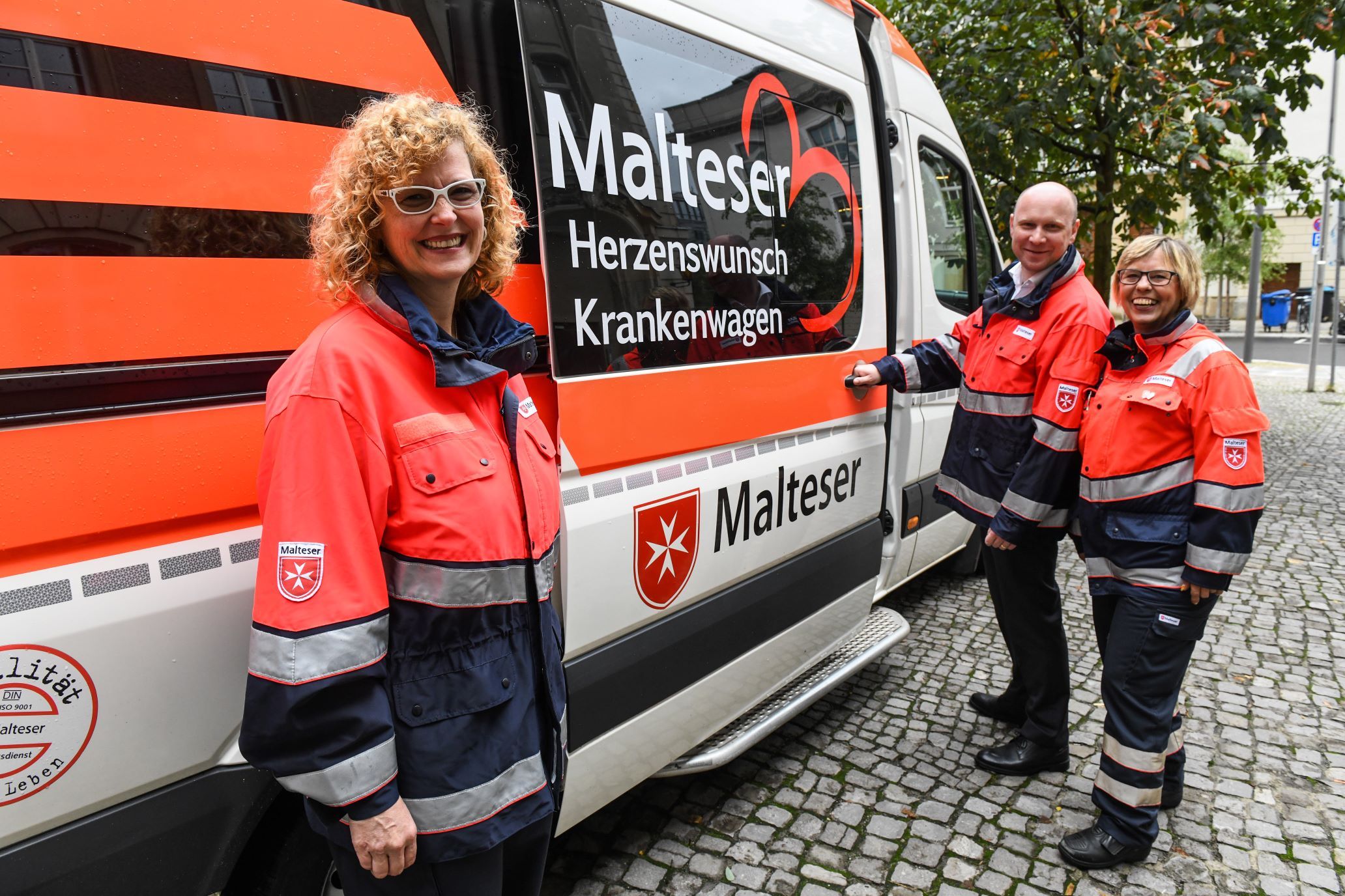 Malteser-Mitarbeitende stehen vor dem Herzenswunsch-Krankenwagen.