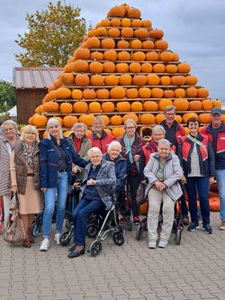 Die Ausflugsgruppe posiert vor einer fast vier Meter hohen Pyramide aus kräftig orangen Kürbissen