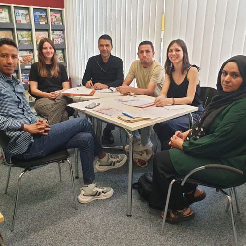 Menschen sitzen in der Bücherei zusammen an einem Tisch