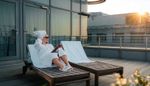 Eine Frau im Bademantel auf einer Liege auf einer Terrasse