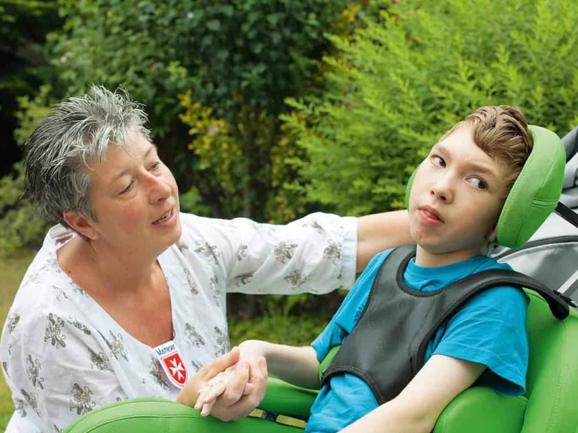 Eine Frau hält die Hand eines Jungen, der in einem Sitz sitzt