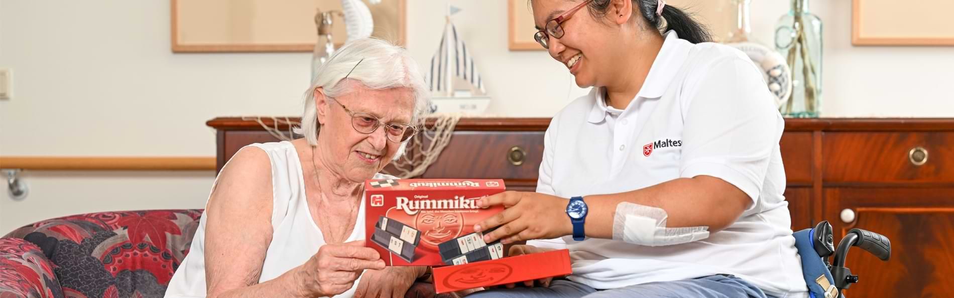 Eine lächelnde Frau im Rollstuhl mit einer älteren Frau