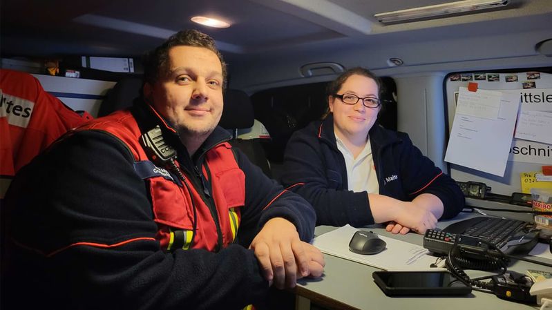 Ein Mann und eine Frau in einem Einsatzfahrzeug der Malteser